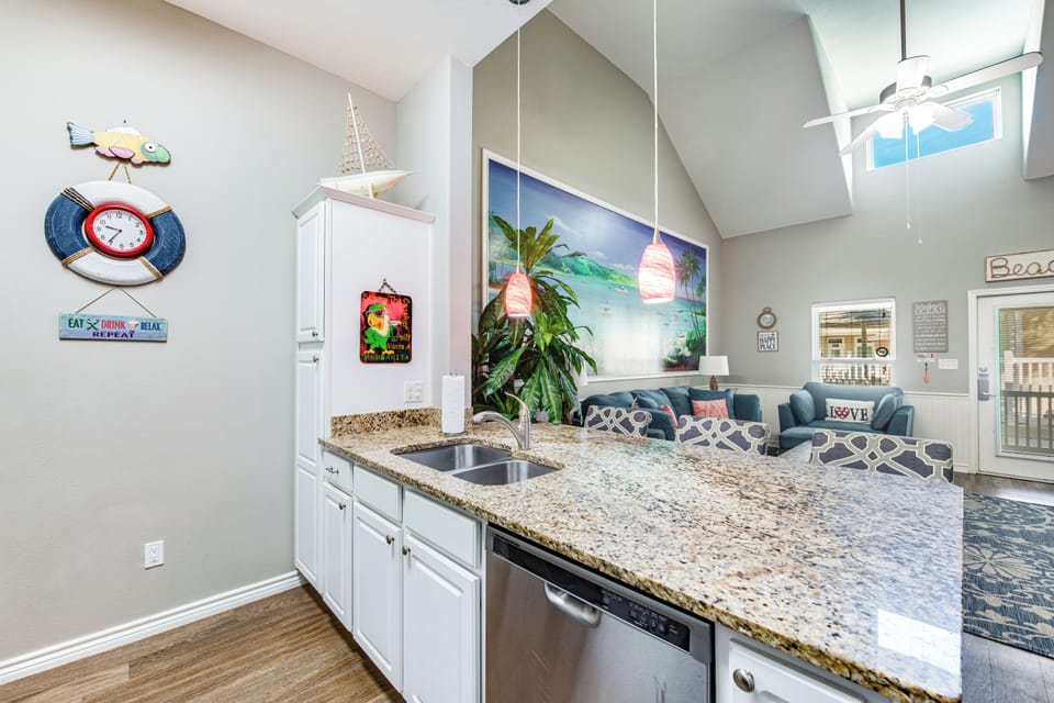Your bright kitchen features granite counters and stainless appliances, flowing into a cozy living area with tropical artwork and skylights.