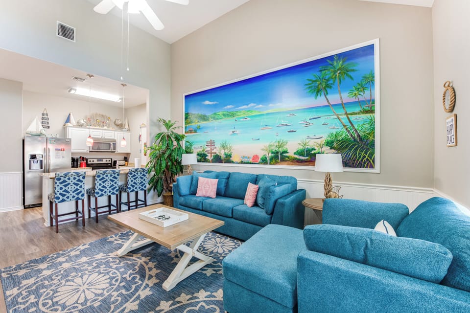 Sink into plush turquoise seating while gazing at tropical paradise artwork. Your open living space flows seamlessly to the kitchen, perfect for gathering.
