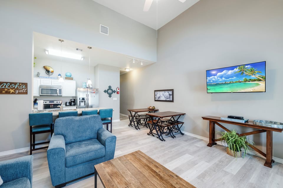 Unwind in your spacious open-plan living area where coastal décor meets modern comfort, complete with kitchen bar seating and entertainment center.