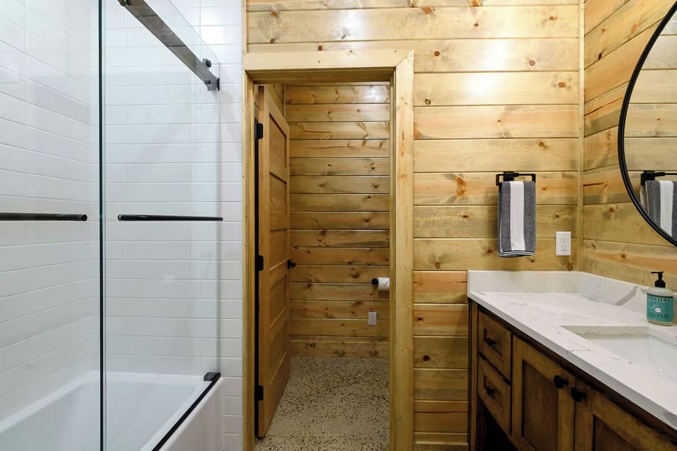 Modern cabin bath with subway-tile tub, quartz vanity, glass doors