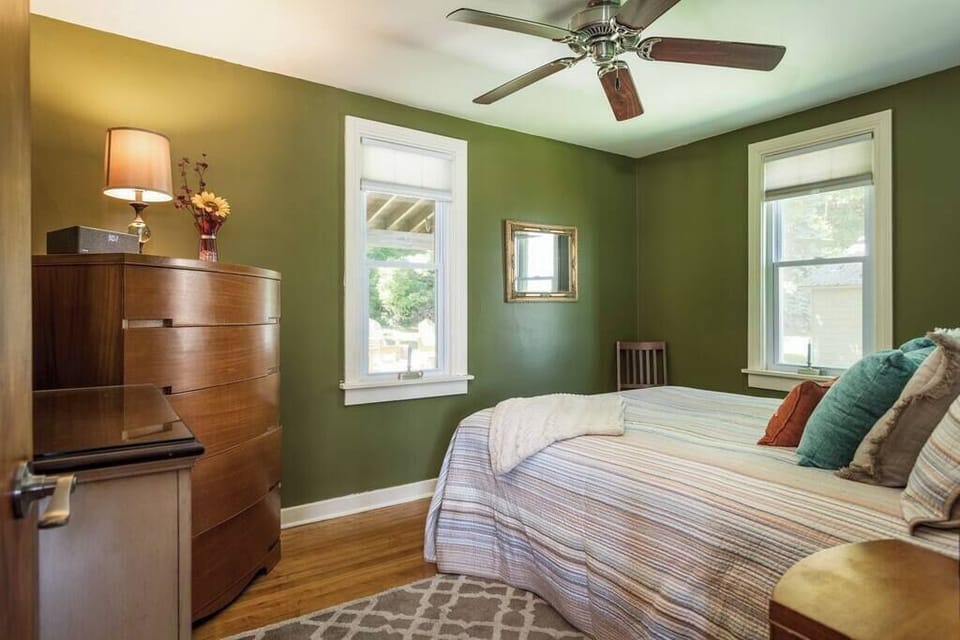 Cozy and calming retreat 🌿

This inviting bedroom features warm wood accents, soothing green walls, and plenty of natural light. A comfortable bed, ceiling fan, and charming touches make it the perfect space to unwind after a day of adventure.