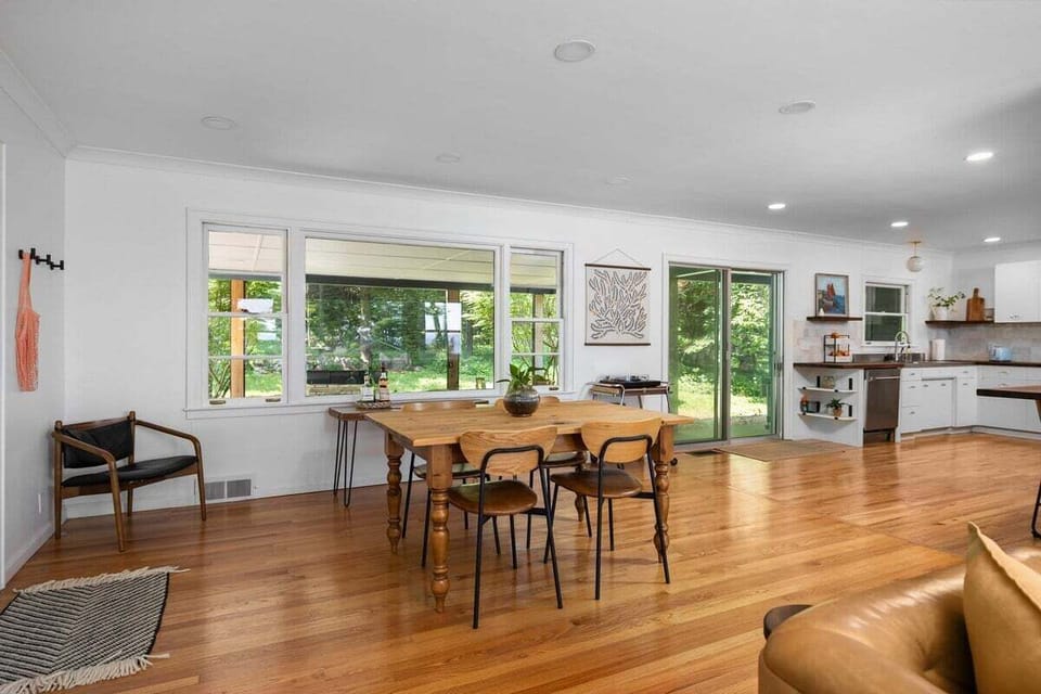 Spacious **open dining and kitchen area** with abundant natural light.

Large windows and sliding doors bring in views of the surrounding greenery, while the dining table provides a comfortable space for meals, games, or gathering together.