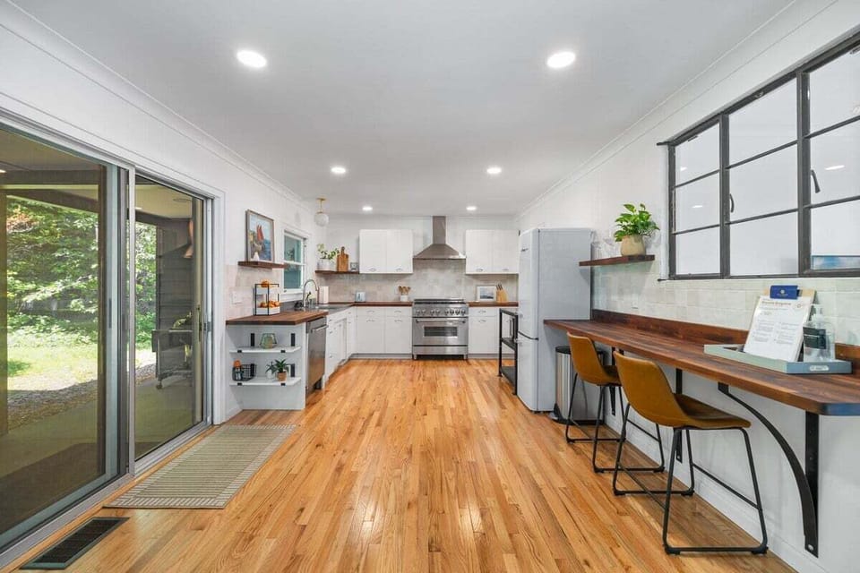 Bright, stylish kitchen with room to gather 🍳

This open-concept space features warm hardwood floors, modern appliances, and plenty of prep space. The extended breakfast bar with seating is perfect for morning coffee or casual meals, and the sliding glass door brings in natural light with easy access to the outdoors. Clean, functional, and thoughtfully designed for cooking and connecting.