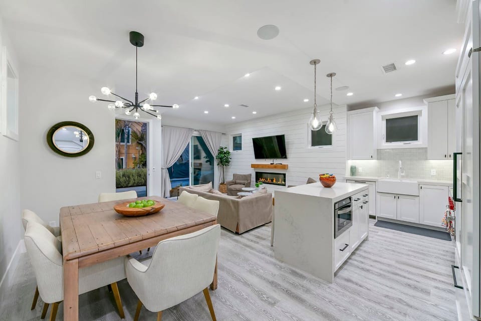 The open-concept dining area features a large wooden table and six contemporary grey upholstered chairs. This space flows seamlessly into the main living floor, making it an ideal setting for hosting dinner parties.