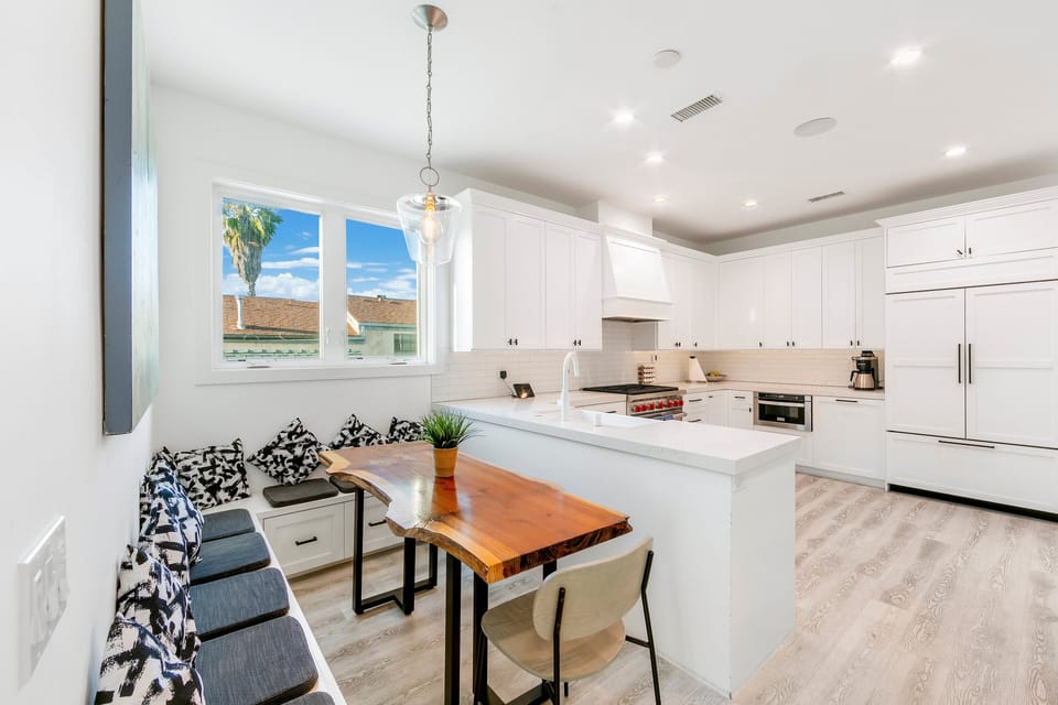 A stylish built-in bench and wooden dining table create the perfect spot for morning coffee or casual family meals right next to the chef's kitchen.