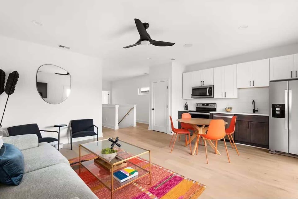 Inviting living area with vibrant accents, comfortable seating, a Smart TV, and a fully equipped kitchen in view, creating an easy flow for relaxing, dining, and gathering. (3rd Floor)