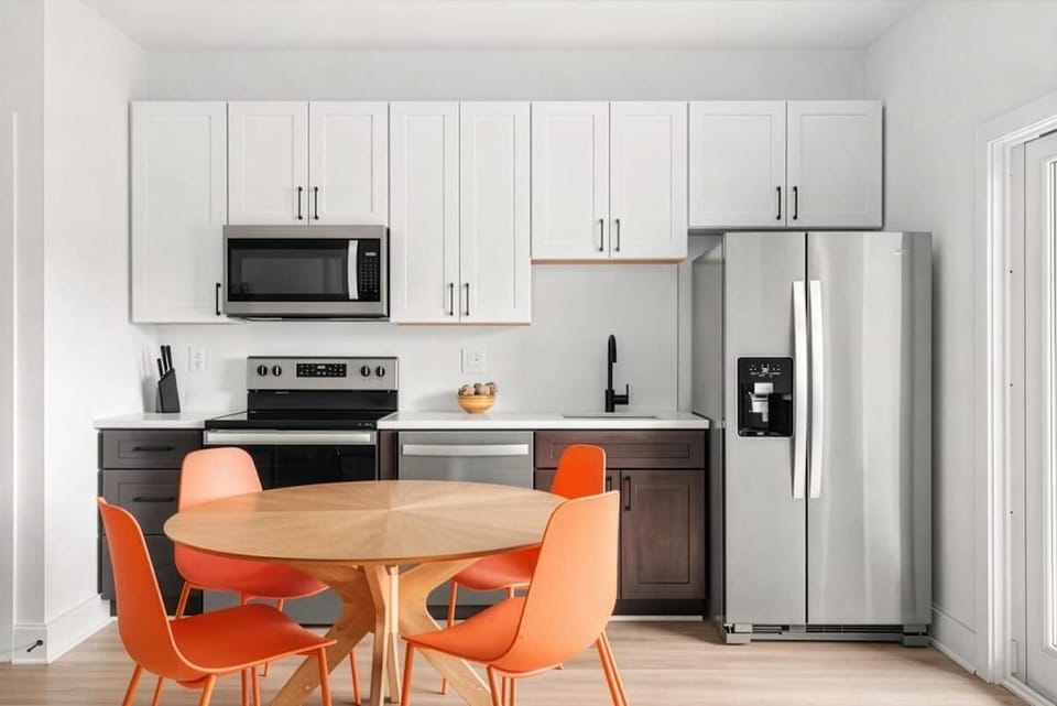 Modern kitchen featuring stainless steel appliances, sleek cabinetry, and a dining table for 4 surrounded by vibrant seating. (3rd Floor)