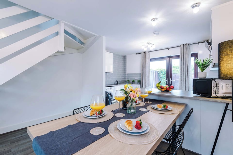 Bright open-plan kitchen and dining space with modern finishes, stylish table setting, and natural light. A welcoming atmosphere designed for comfort and gatherings.