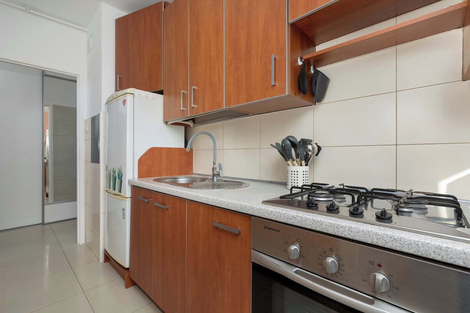 6.  The opposite view of the kitchen, revealing a full-size white refrigerator next to the wooden cabinets and a large range stove.