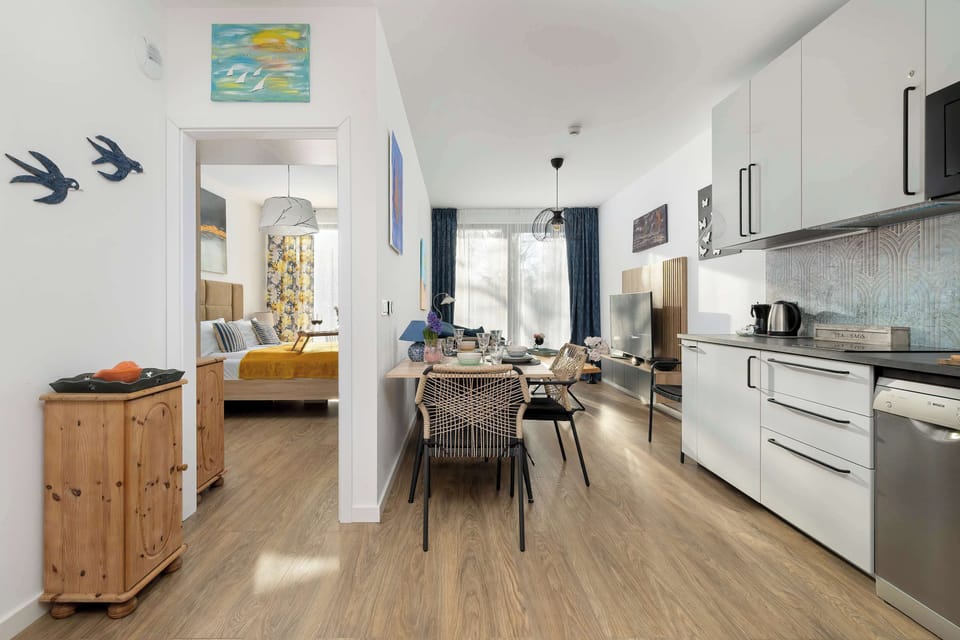 A functional hallway that leads from the kitchen toward the bedrooms and bathroom. A small wooden cabinet and simple wall decor maintain the minimalist aesthetic.