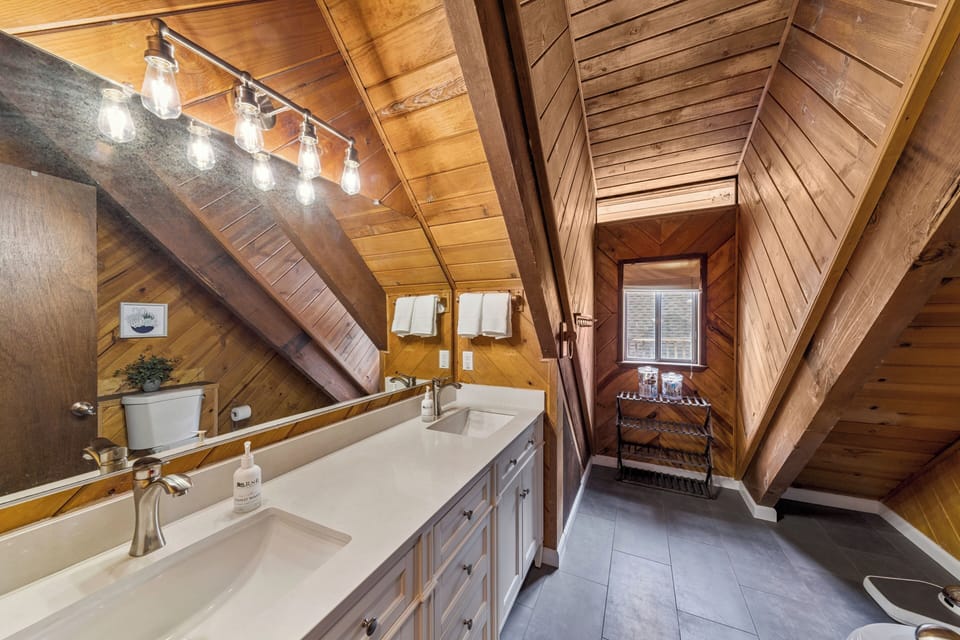 Unwind in this charming wood-lined bathroom where rustic beams meet modern comfort, creating your perfect mountain retreat sanctuary.