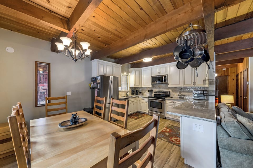 Gather around your cozy wooden dining table beneath exposed beams in this open-concept space where rustic charm meets modern convenience.