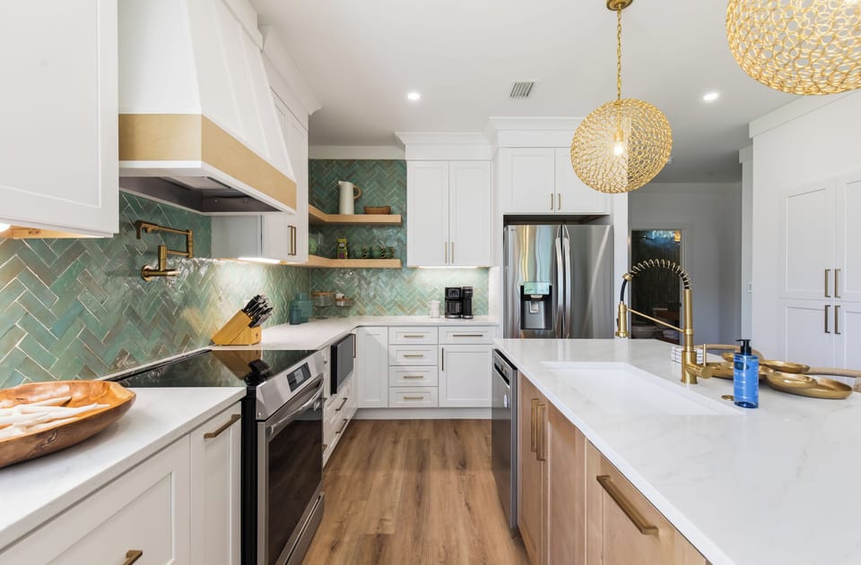 A completely renovated kitchen featuring a striking green herringbone backsplash and gold accents.
