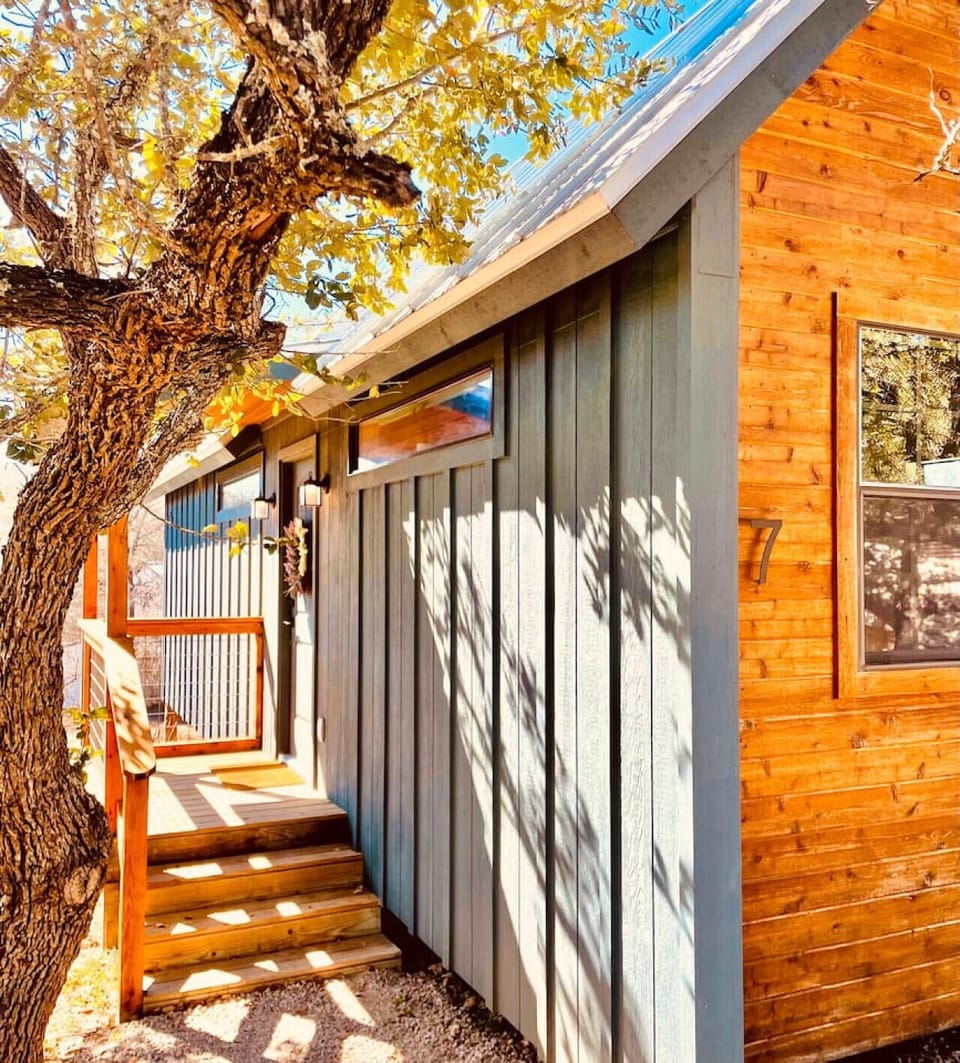 A welcoming cabin entrance surrounded by golden autumn foliage and warm wood accents.