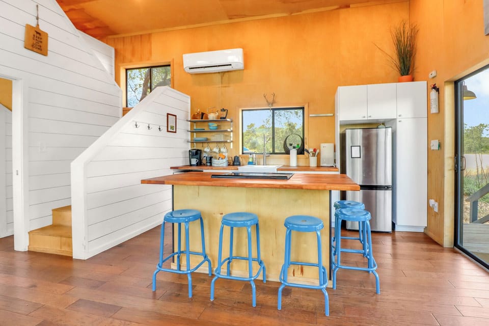Inviting kitchen island with cheerful blue stools, where you'll find everything you need to prepare meals in a bright, warmly-lit space with modern appliances and stunning natural views.