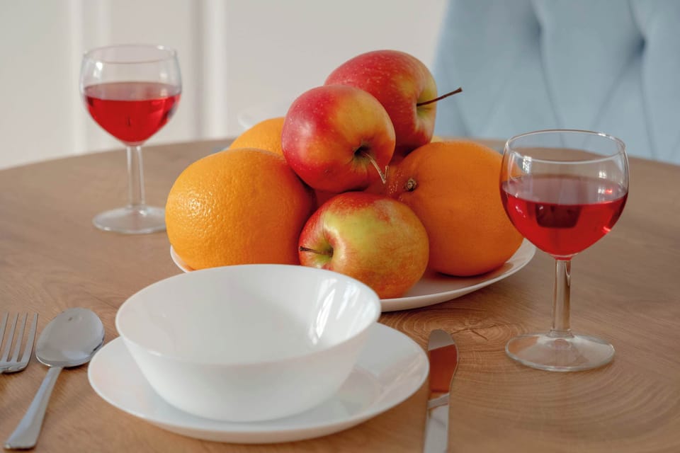 A close-up of a table setting featuring fresh fruit and glasses of red wine, adding a welcoming, homely touch to the dining area.