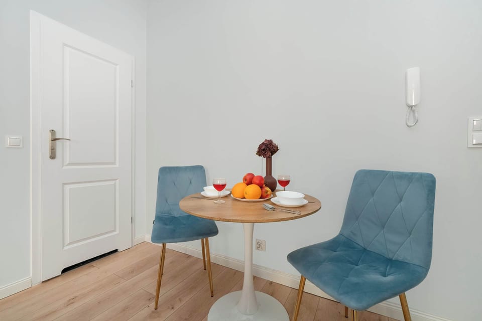 A small dining setup with a round table and two blue chairs, ideal for a cozy meal or morning coffee.