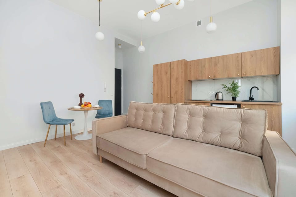 A wider shot showing the open layout of the studio with the sofa, kitchenette, and dining area all visible, giving a sense of the space’s flow.