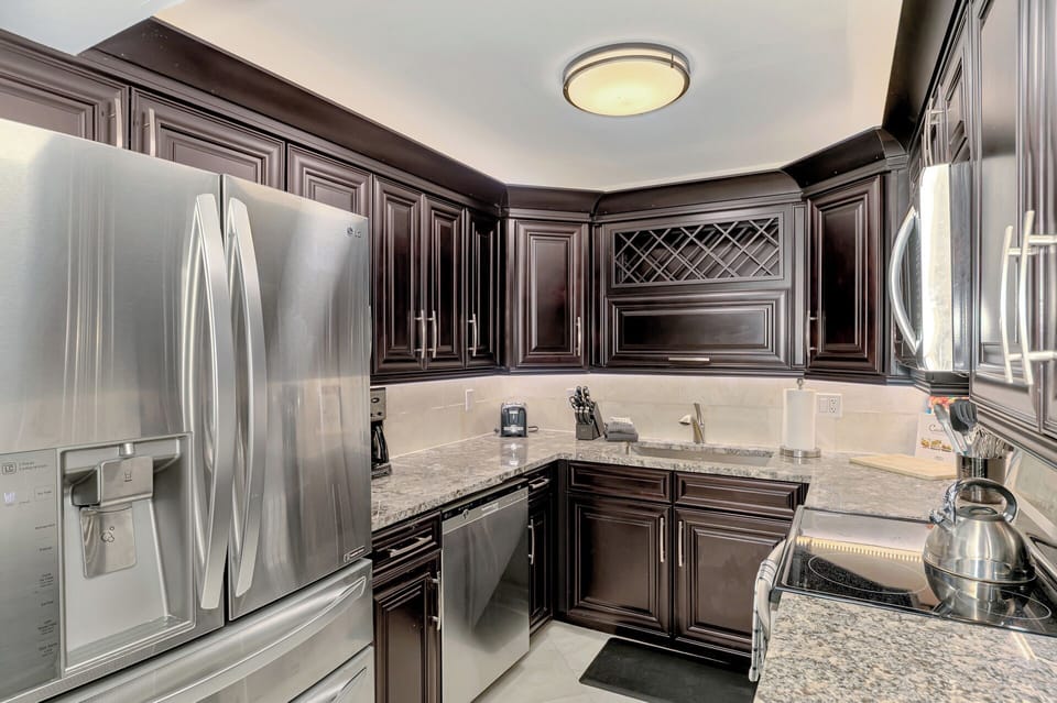 Your gourmet kitchen features rich dark cabinetry, granite countertops, and premium stainless steel appliances for memorable meal preparations.