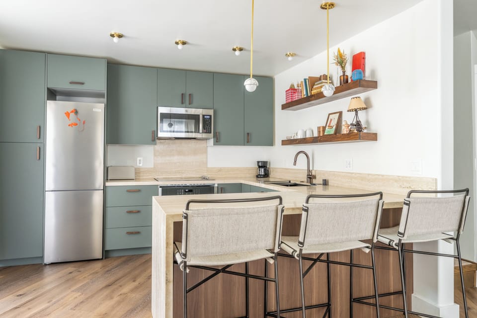 Your modern kitchen invites culinary adventures with sleek sage cabinets, gleaming countertops, and a breakfast bar perfect for morning coffee or casual dining.