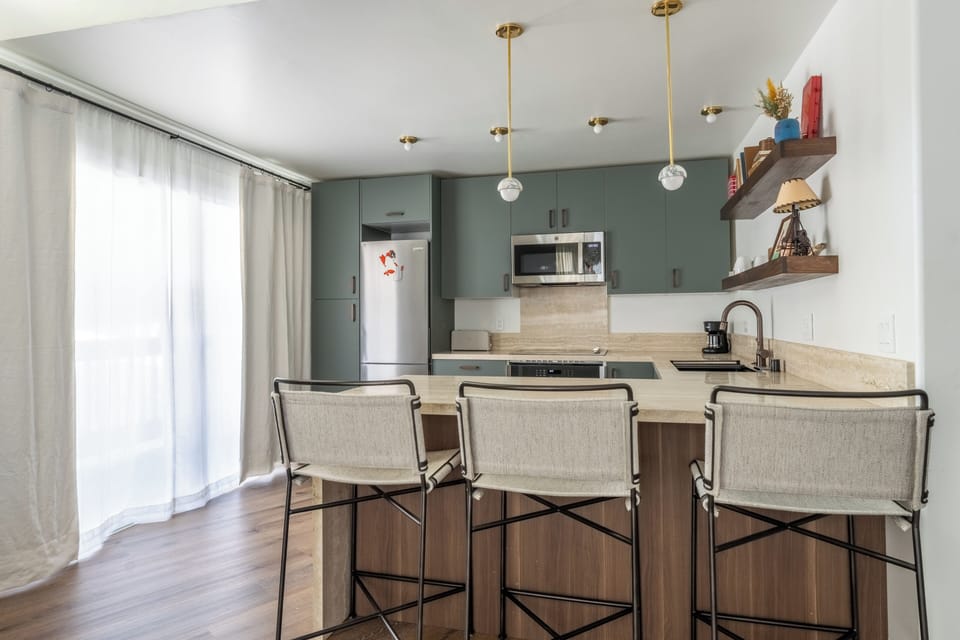 Your stylish kitchen features sage cabinets, pendant lighting, and breakfast bar seating where you can enjoy morning coffee.