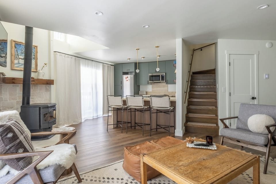 Unwind in your stylish open-plan living space featuring a cozy fireplace, modern kitchen, and warm wood accents perfect for relaxing.