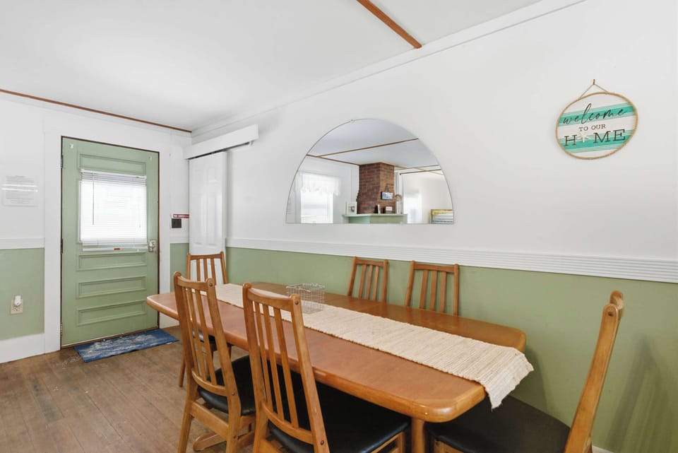 The dining area seats six for bigger group meals, tucked alongside the kitchen with a cottage-green accent wall giving it some character.