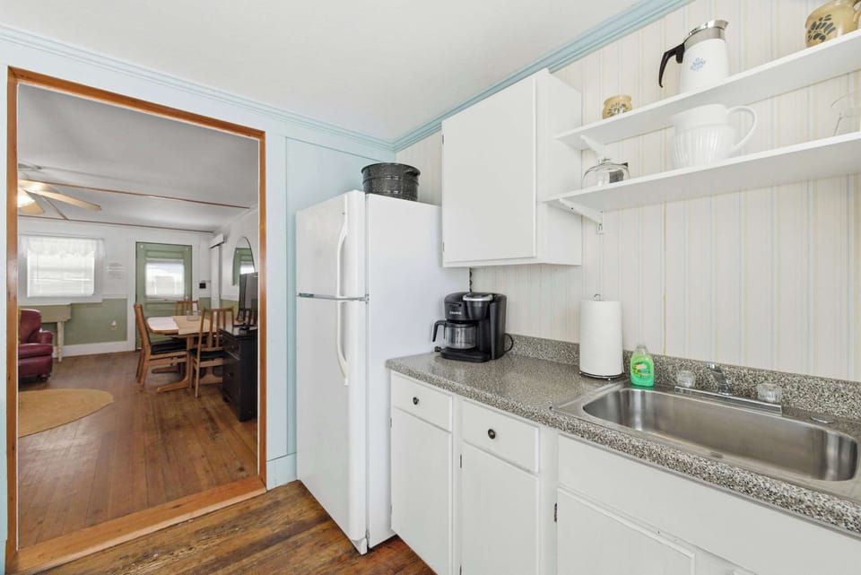 The kitchen has everything you need for a full stay — gas range, full-size fridge, drip coffee maker, and a clear sightline through to the dining room beyond.