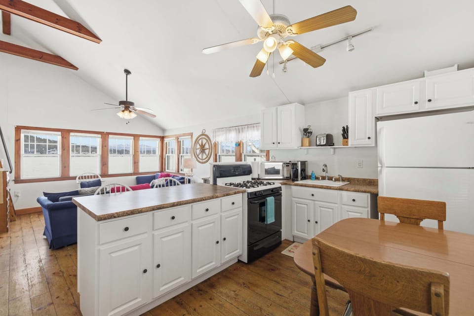 The kitchen flows right into the living and dining area, with white cabinets, a full-size fridge, and a dining table that seats four just steps from the water views.