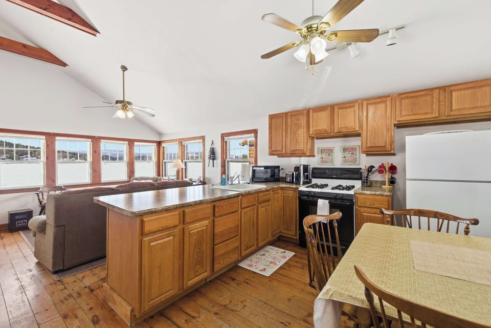 The kitchen and dining area share the same open space, with pine floors and lake-facing windows keeping everything bright.