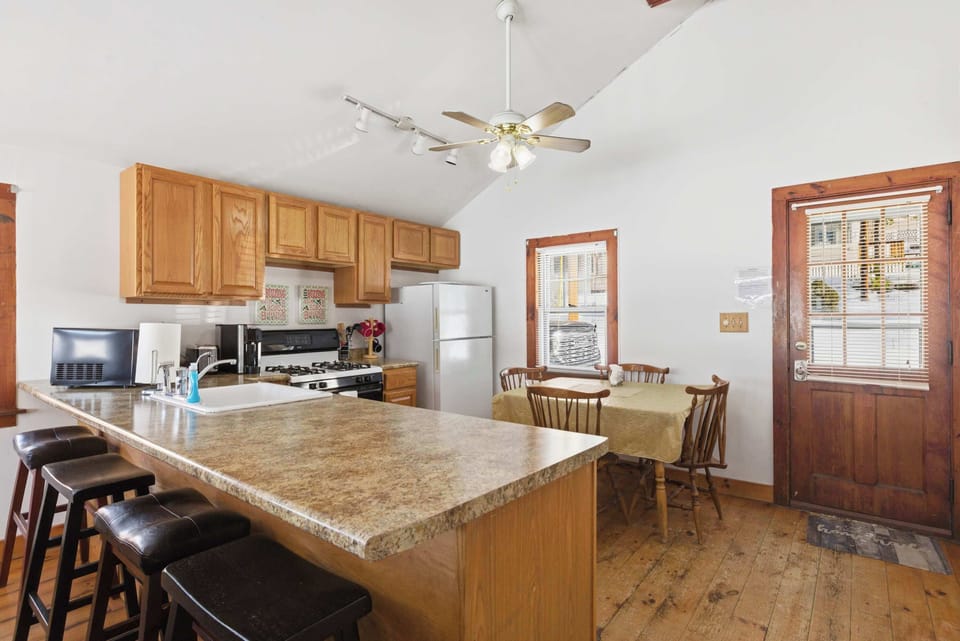 The full kitchen layout — breakfast bar, gas range, and full-size fridge all within easy reach of the dining table.