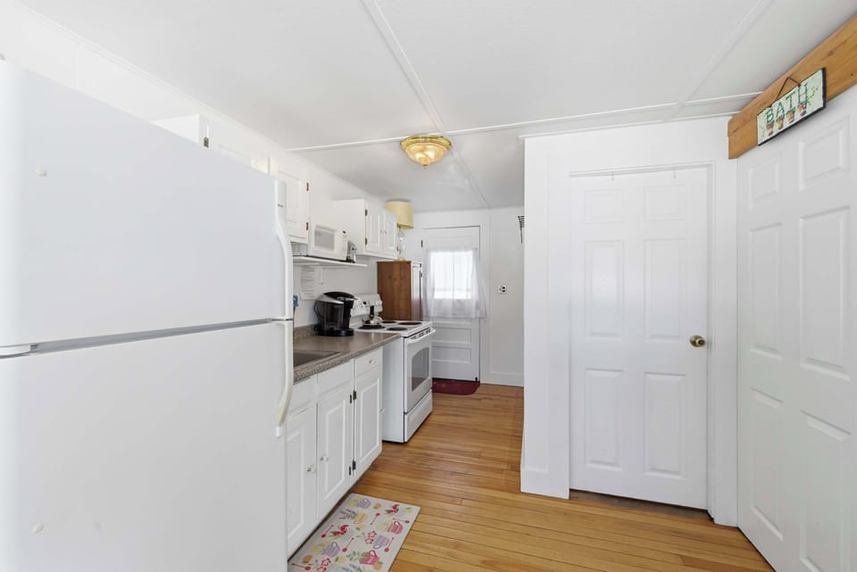 The full-size refrigerator and range side by side — the kitchen is compact but fully stocked for real cooking.