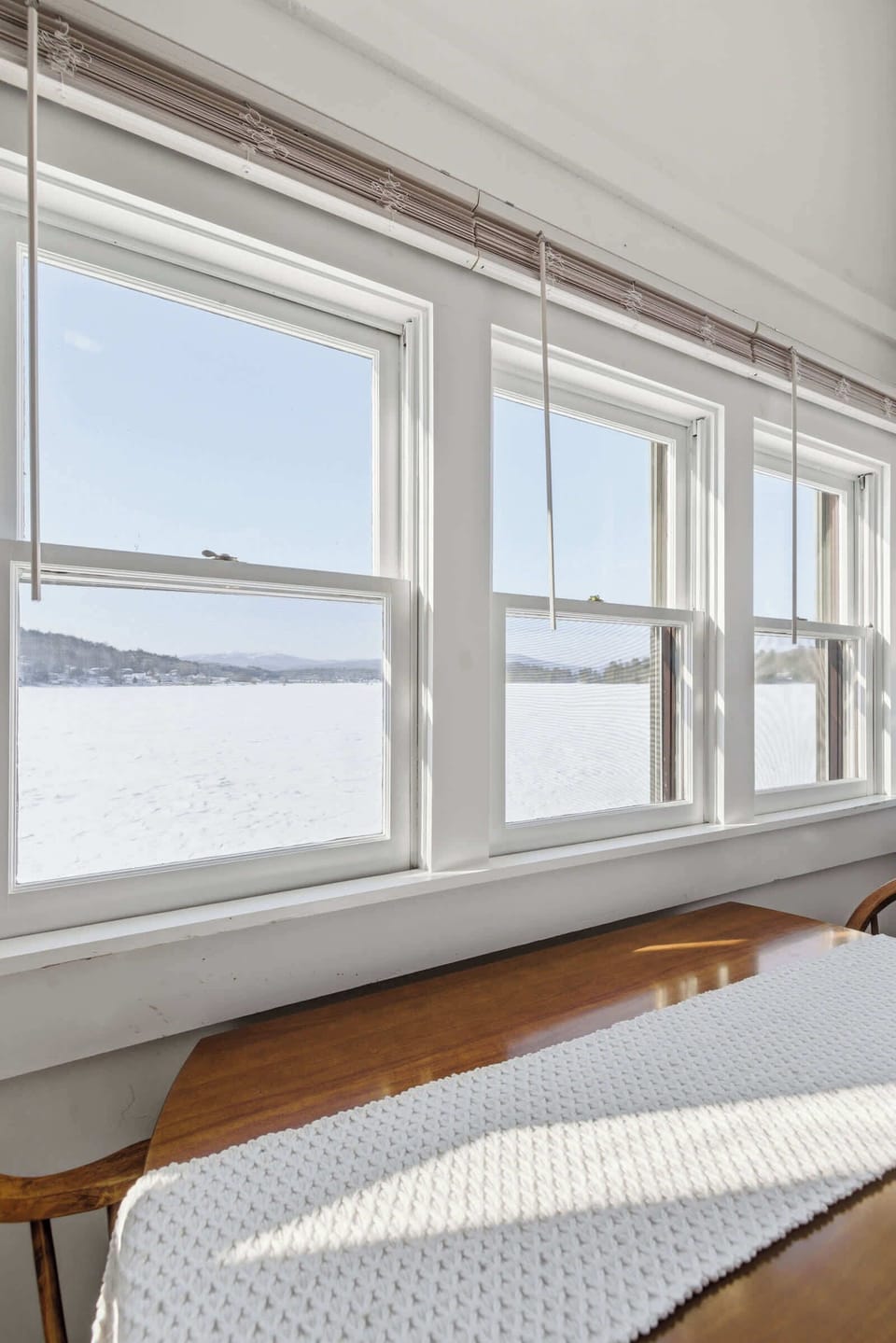 The lake view through the cottage windows in winter — even off-season, the water and light make this a hard seat to leave.
