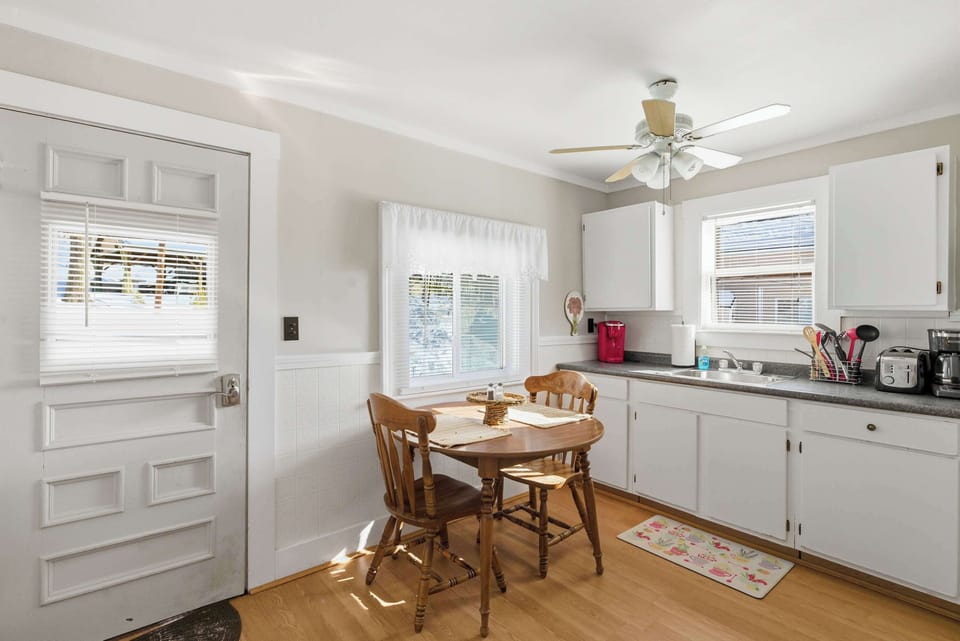 A bright, clean second kitchen view showing the dining nook and white cabinetry — compact but well laid out for everyday use.