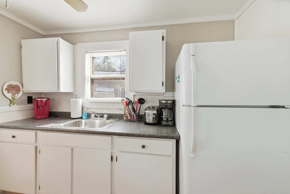 The kitchen has everything you need for real cooking — full-size refrigerator, ample counter space, and a window that lets in plenty of natural light.