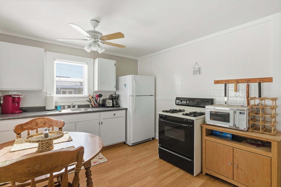 The fully equipped kitchen has a gas range, full-size refrigerator, and a dining table for 3–4 — everything you need to cook a real meal without hunting for anything.