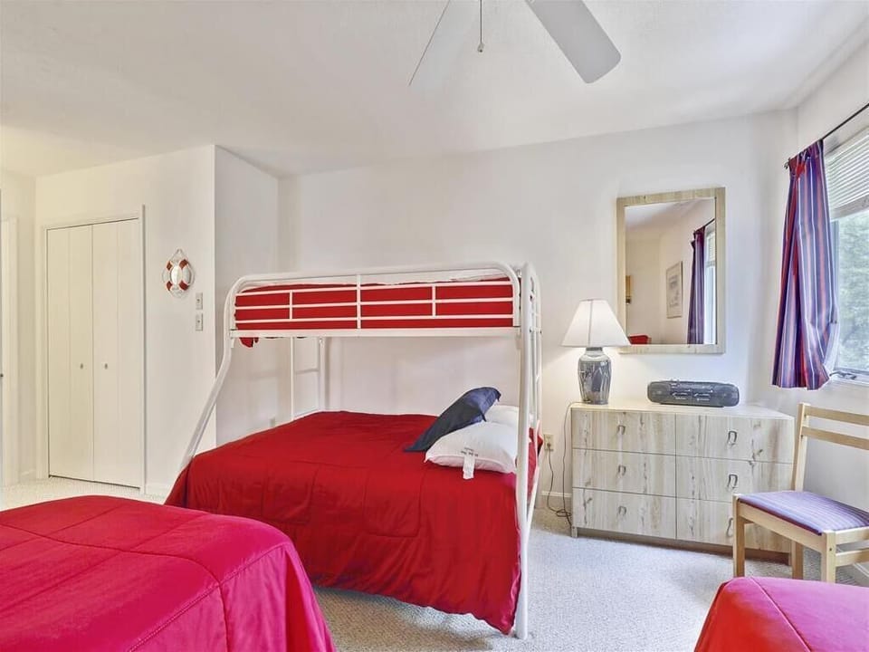 Cozy sleeping arrangements with vibrant red bedding and a fun bunk bed for the little ones.
