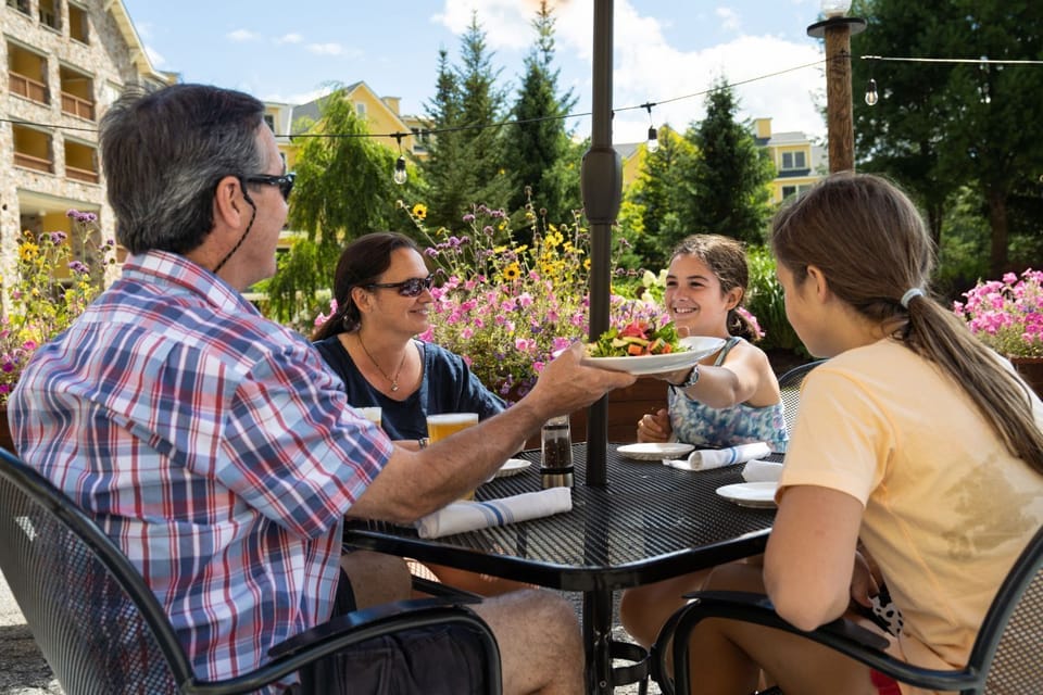 Guests enjoy alfresco summer dining at Coleman Brook Tavern, surrounded by flowers and mountain views at South Face Village Condominiums.