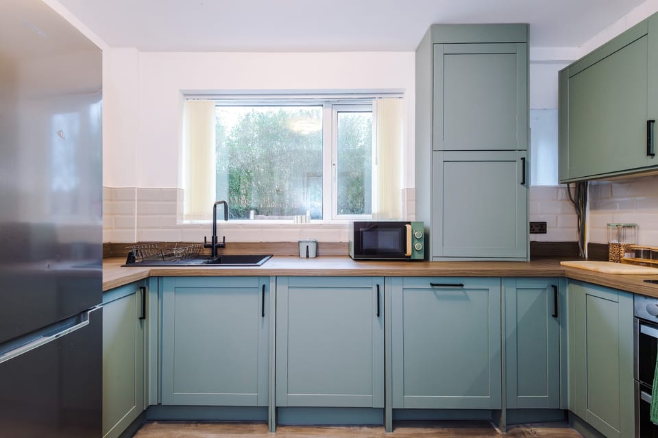 Kitchen: Bright space with teal cabinets and sunlight streaming through; perfect for culinary adventures!