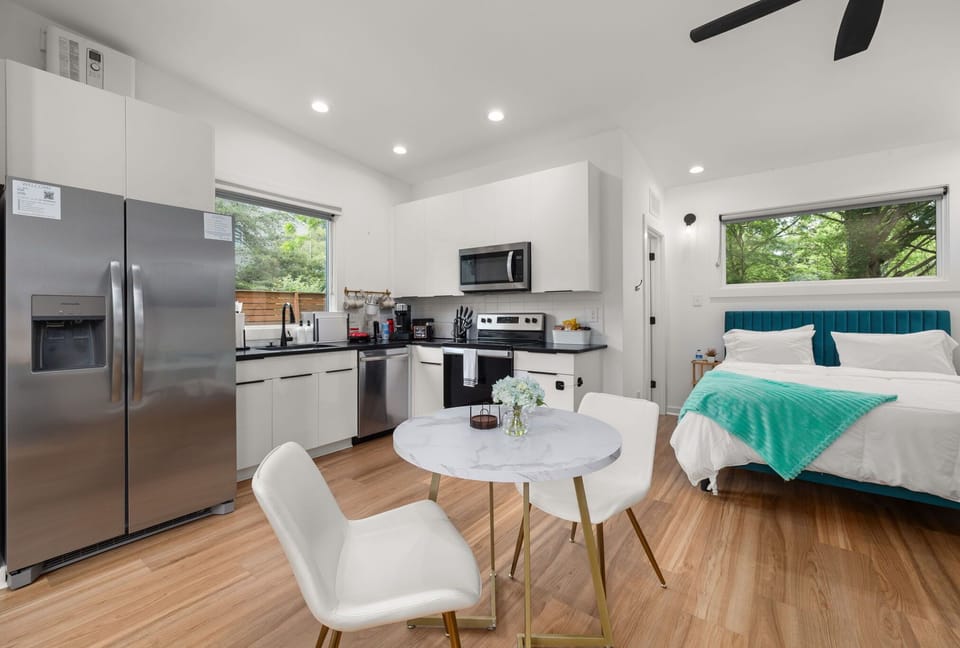 Bright modern studio with full kitchen, dining nook, and lush window views