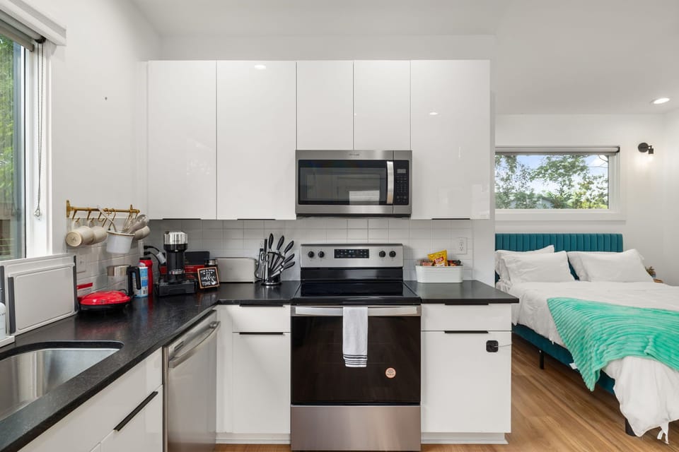 Bright studio with sleek full kitchen and cozy bed by sunny windows