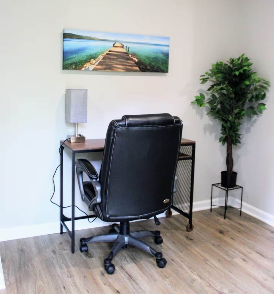 Workspace with desk, rolling chair, and table lamp