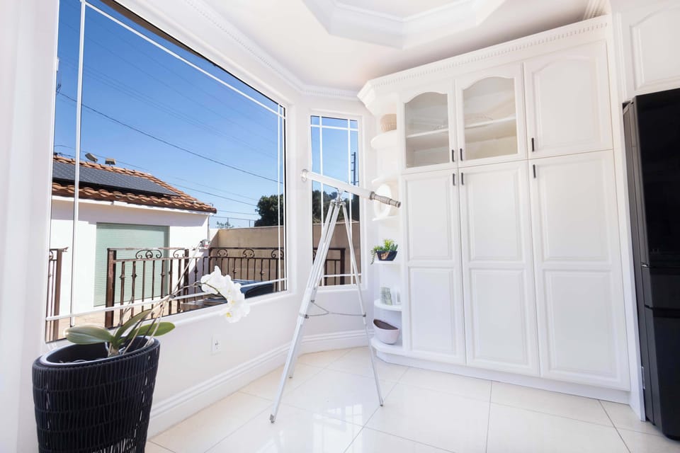 Sunlit kitchen corner with large windows and a telescope for enjoying the view.