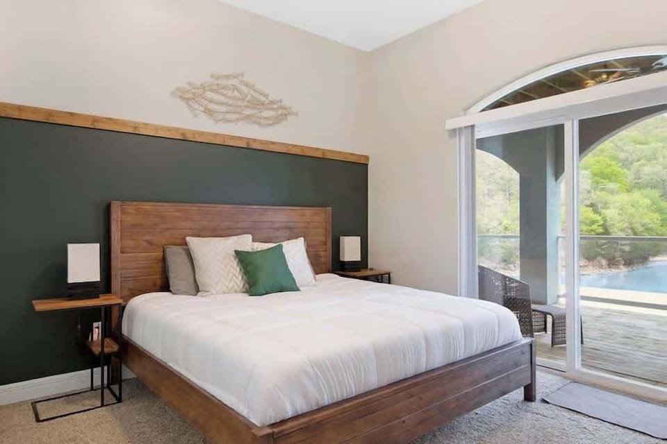 Enjoy a peaceful night's sleep in this spacious bedroom featuring a comfortable king bed, vaulted ceiling, and large windows.