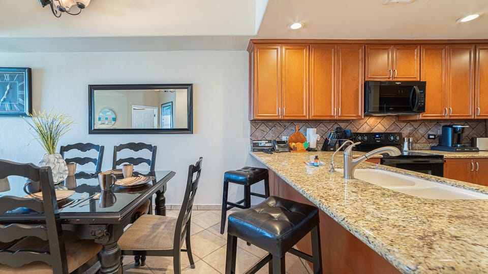 The dining table site near the kitchen counter and bar stools.