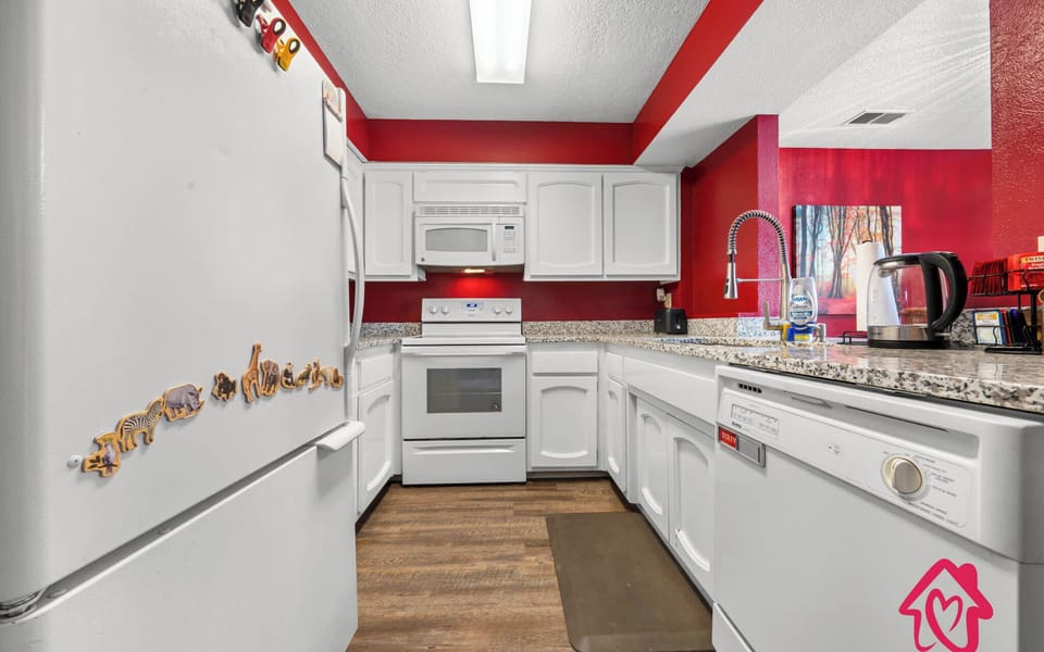 Modern kitchen with granite countertops and red walls.