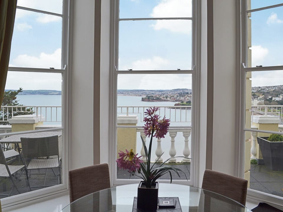 The dining area is situated in front of the curved windows offering an unparalleled view across the bay | Apartment 8 - Astor House, Torquay