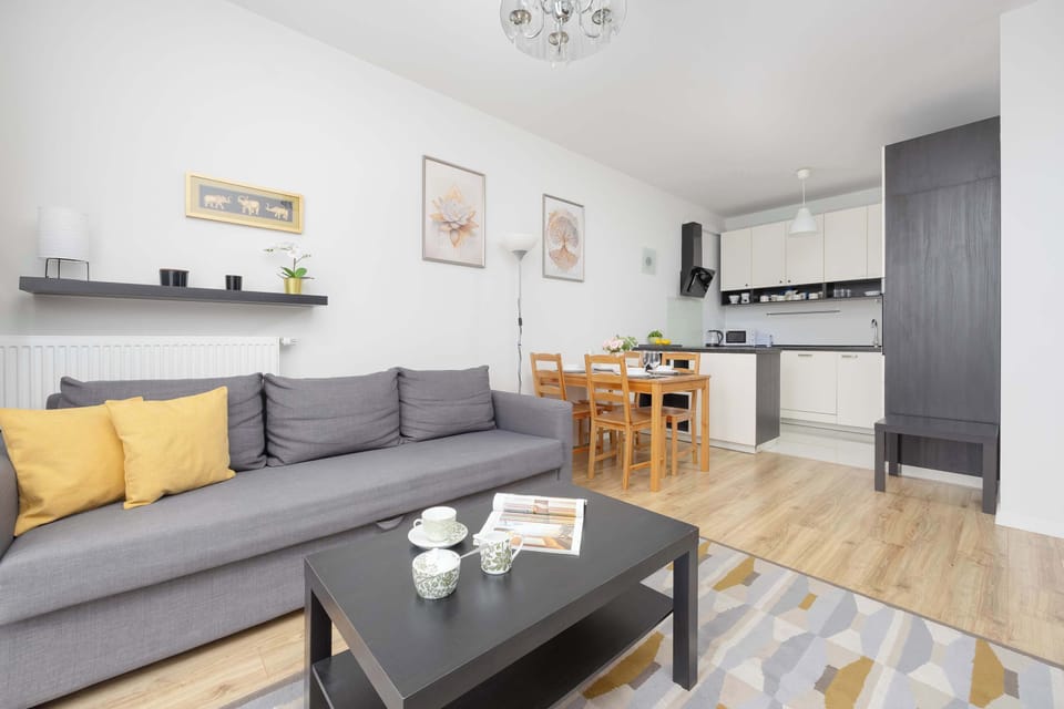 A cozy living room with a sofa bed and coffee table, ideal for relaxing or watching TV with family and friends. Light-colored walls and wooden floors create a welcoming atmosphere.