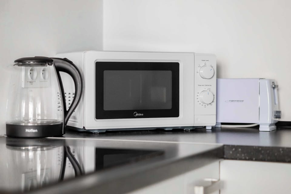 A closer look at the kitchen counter, featuring a kettle and microwave. Sleek surfaces and minimalist style enhance the space.