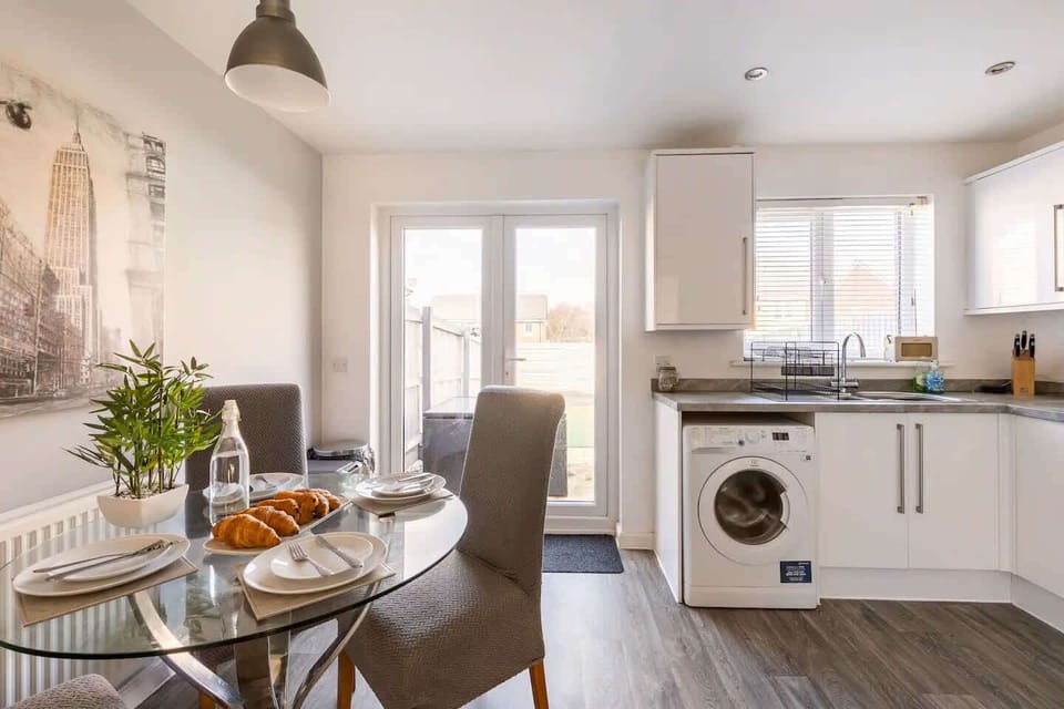 Cook in a sleek kitchen, then dine at a chic glass table set for three. With modern décor, warm lighting, and double doors to the outdoors, this space blends comfort and style.